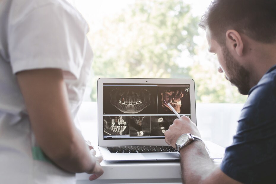 hombre-dentista-explica-radiografías-dentales-a-una-mujer