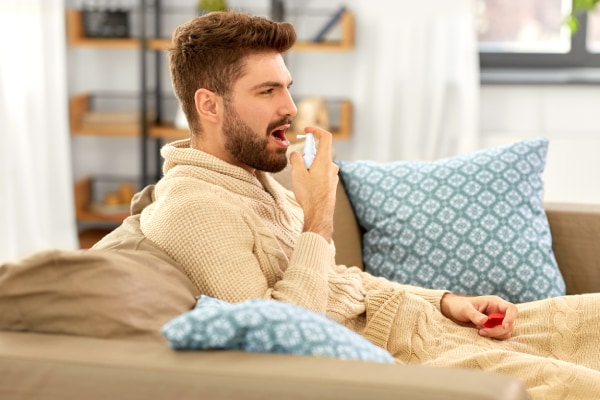 Hombre aplicandose spray bucal para mal aliento